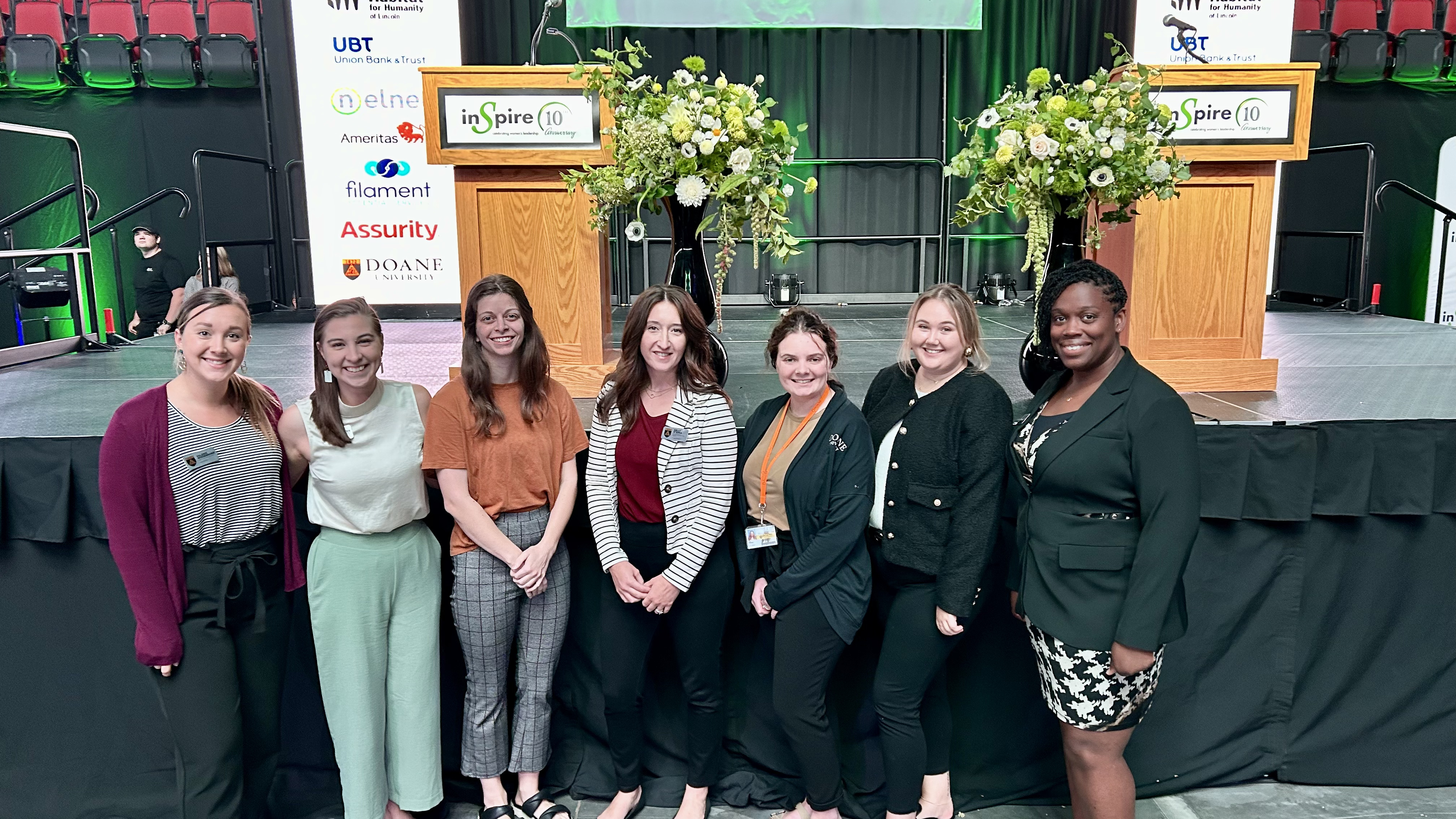 Employees of doane stand near the stage at the 2024 Inspire Women Awards