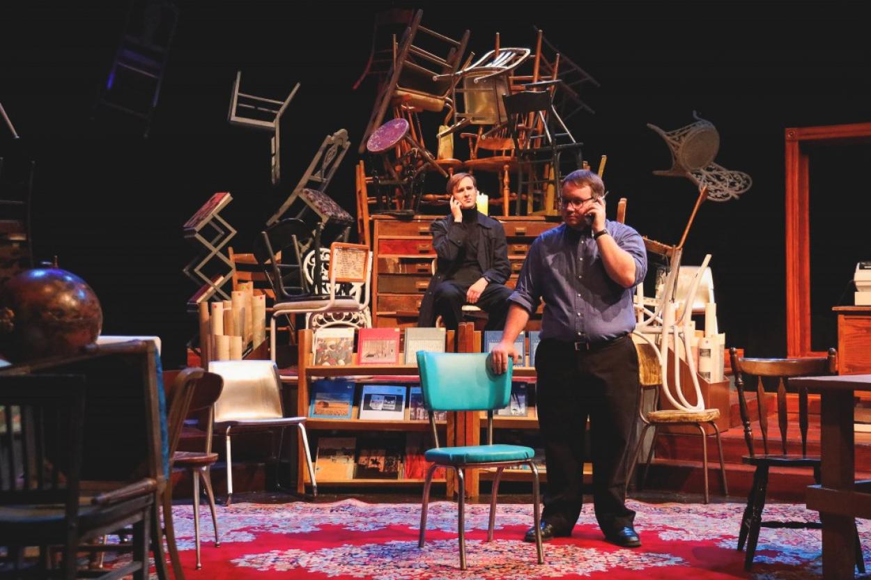 The set of "Lonely Planet" shows actors in front of haphazardly stacked chairs.