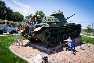 volutneers repaint the military tank in Seward, Nebraska